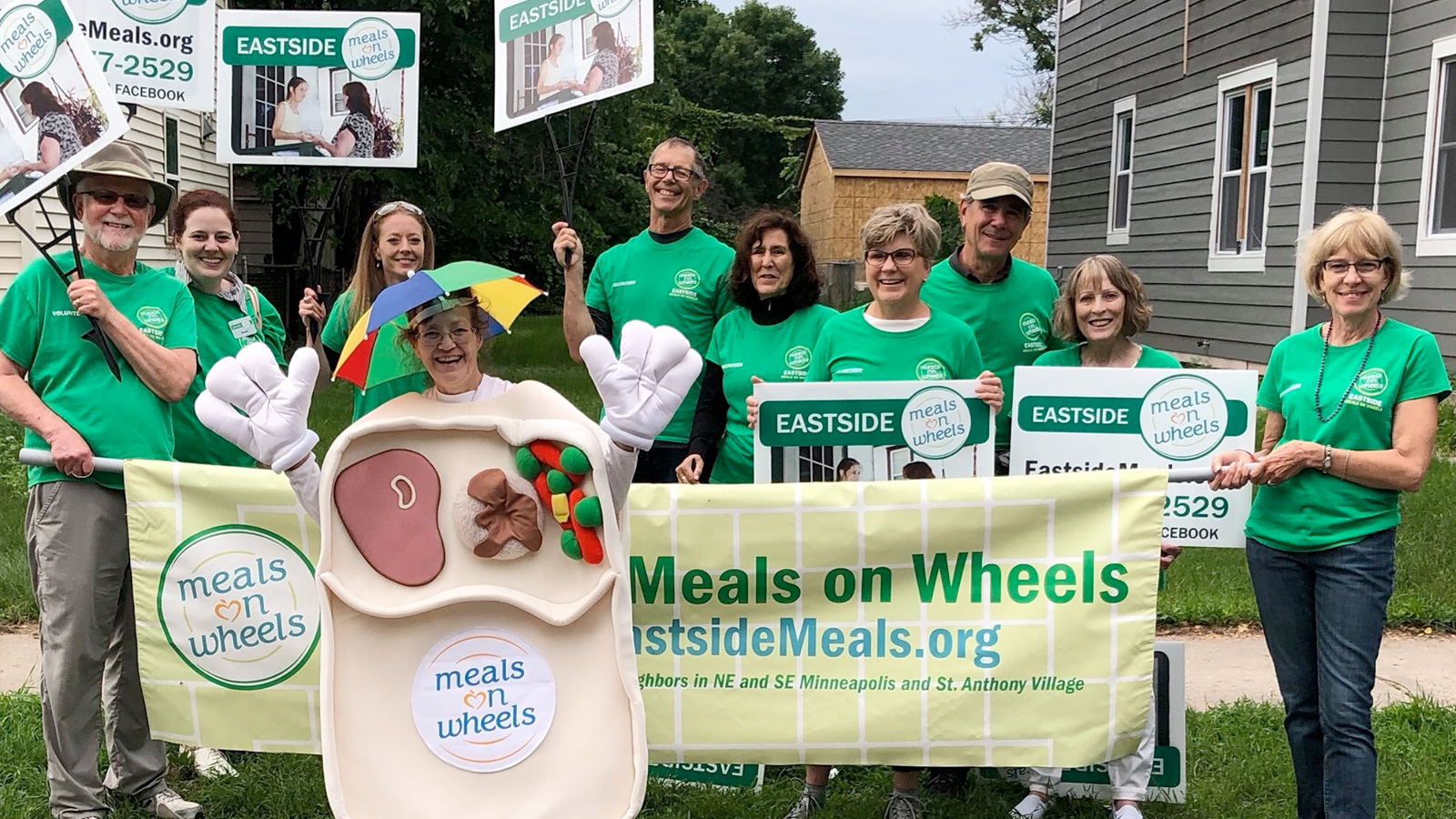 EMOW staff and volunteers holding signs and wearing green at the NE Parade