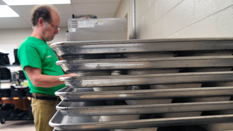 EMOW employee loading oven trays with meals