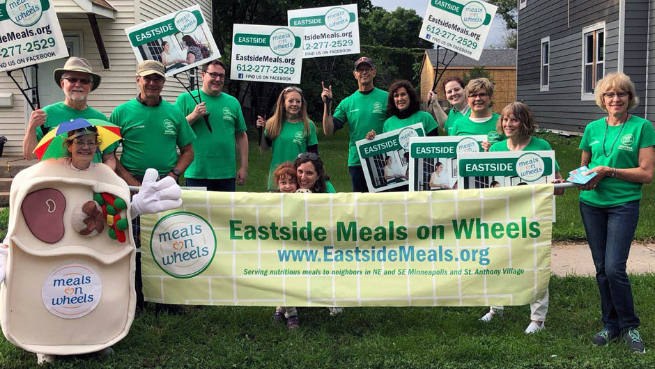 EMOW volunteers holding signs and wearing green at the NE Parade