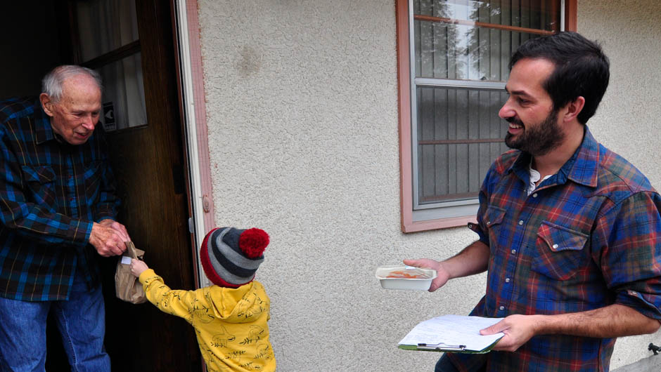 Parent watches as their kid delivers a meal to an EMOW client